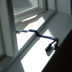 Flexible black power extension cord on a white window sill in daylight, for portable energy solutions.